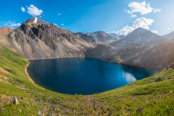 istock Panoramic spring view to round mountain lake on background of mountains. Gorgeous blue mountain lake in mountains with azure big pond while hiking. 1342065800