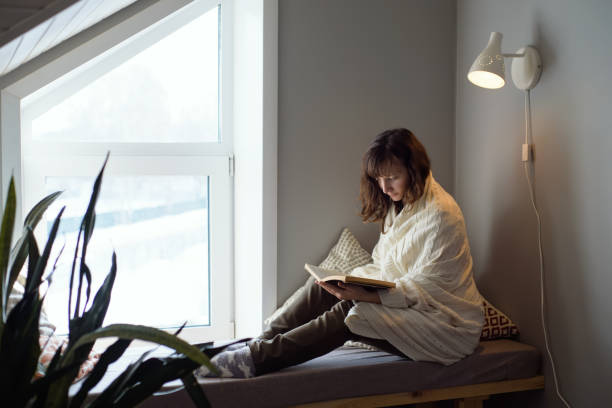 istock A woman is sitting by the window and reading a book. Autumn training 1342065892