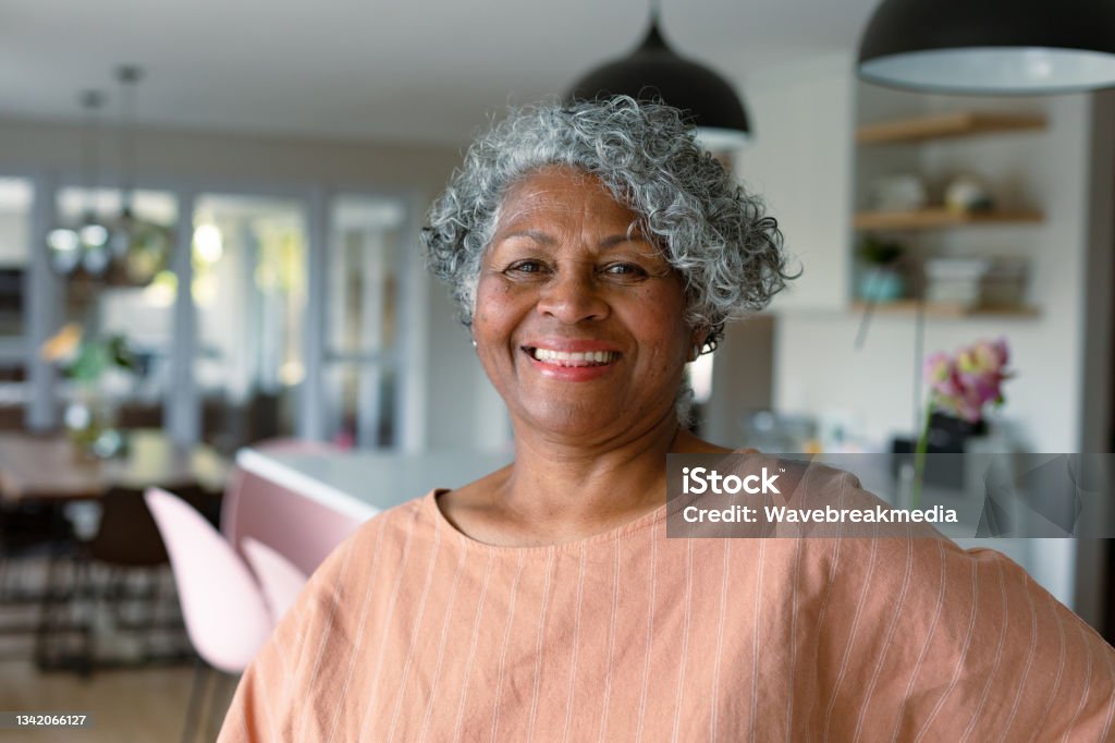 Happy african american senior woman standing standing in kitchen and looking at camera Happy african american senior woman standing standing in kitchen and looking at camera. active retirement lifestyle at home. Senior Adult Stock Photo