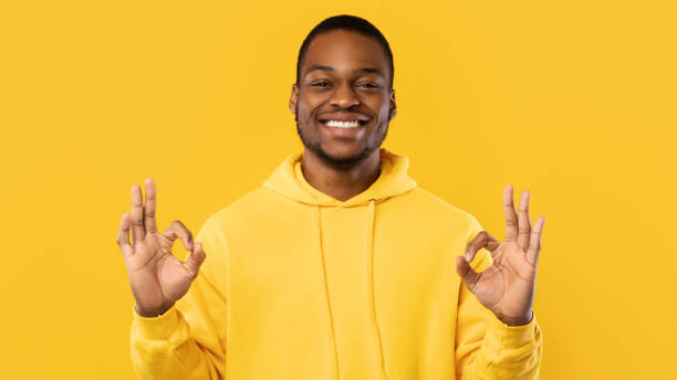 istock Black Guy Gesturing Okay Sign Standing In Studio, Yellow Background 1342067176