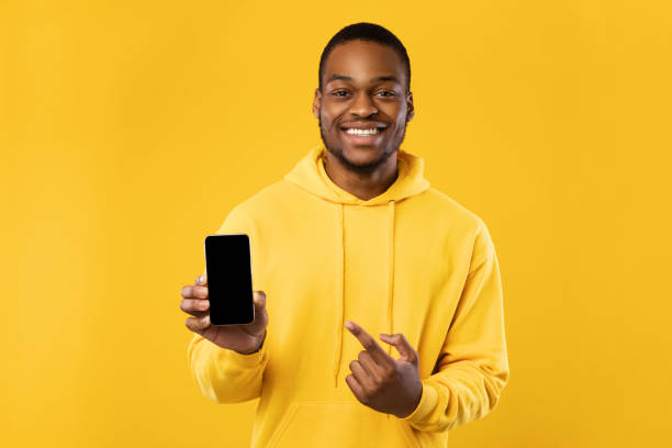 istock Black Man Showing Phone Pointing Finger At Screen, Yellow Background 1342067749