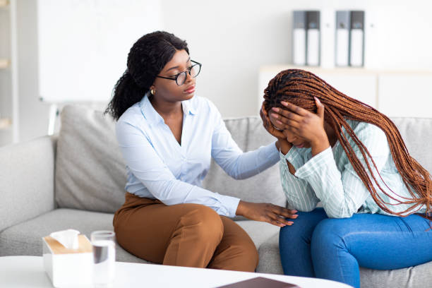 istock Stressed black lady suffering from depression, her counselor supporting her at medical office 1342067973