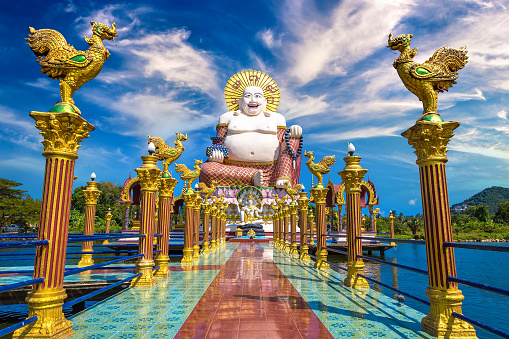 Giant smiling or happy buddha statue in Wat Plai Laem Temple, Samui, Thailand in a summer day