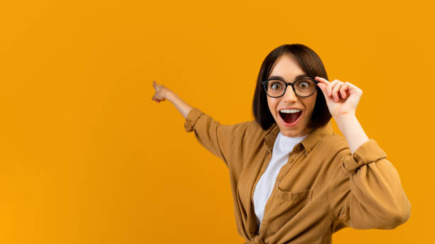 istock Seasonal sale. Surprised lady pointing at empty space over yellow studio background, banner design, panorama 1342068774