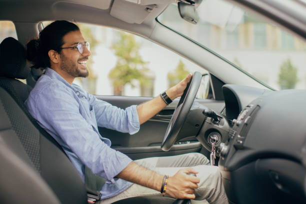 istock Handsome middle-eastern man driving auto, holding hand on gear 1342068783