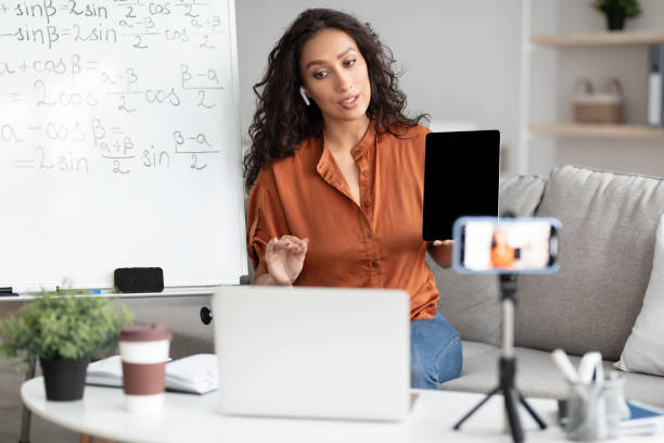 istock Female teacher explaining math online showing tablet to laptop 1342068890