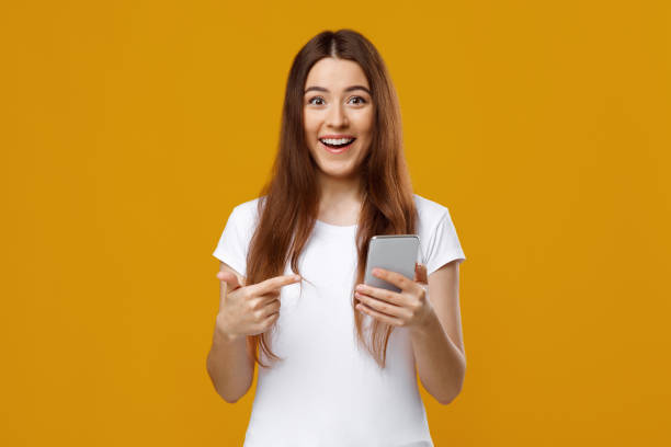 istock Amazed pretty woman pointing at smartphone in her hand 1342068991
