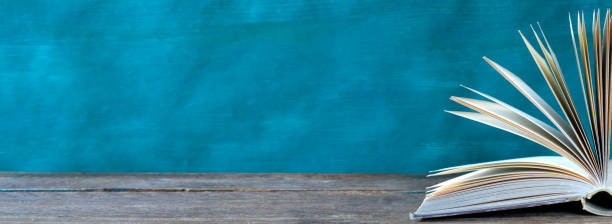istock Open book, hardback books on wooden table on teal background. Back to school,education,reading. Copy space 1342069073