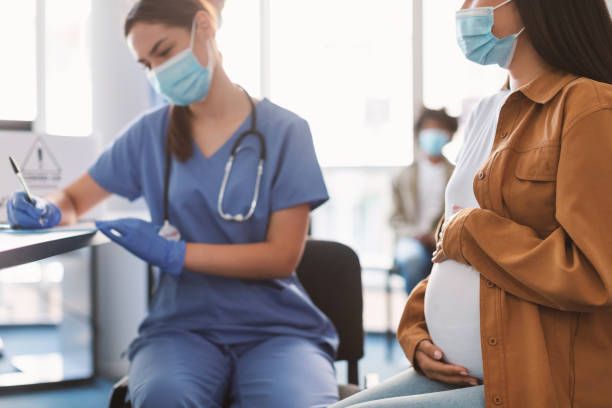 schwangere dame in maske bei termin in der arztpraxis - obstetrician stock-fotos und bilder