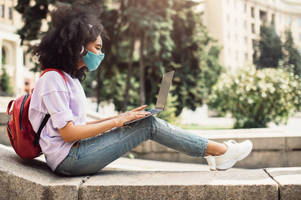 istock African American Girl Browsing Internet On Computer Wearing Mask Outdoors 1342070507
