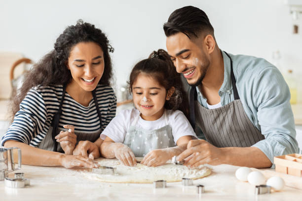 istock Positive arab father, mother and daughter making biscuits, wearing aprons 1342072998
