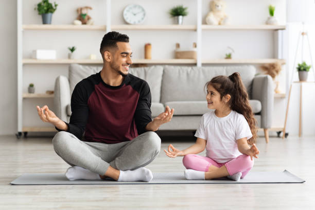 istock Cheerful father and daughter meditating together at home 1342074890