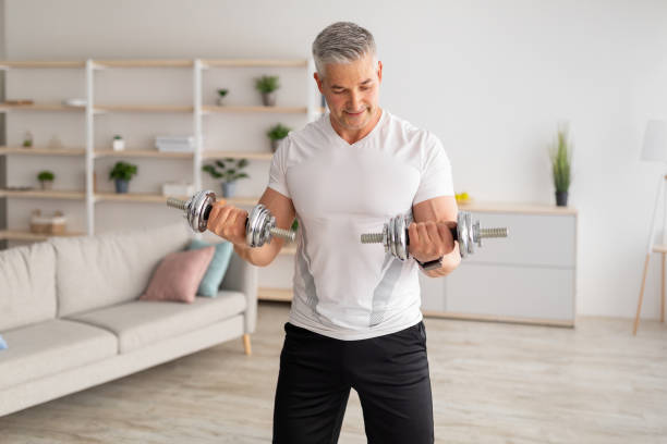 istock Workout during lockdown. Athletic middle-aged man doing dumbbell workout at home, training in living room 1342074997