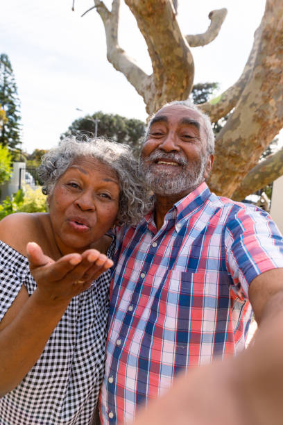 happy couple afro-américain de personnes âgées prenant un selfie et envoyant des baisers - couple black american culture kissing photos et images de collection
