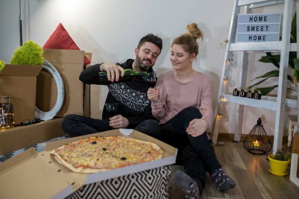 istock Couple surrounded by cardboard boxes eating pizza 1342075423