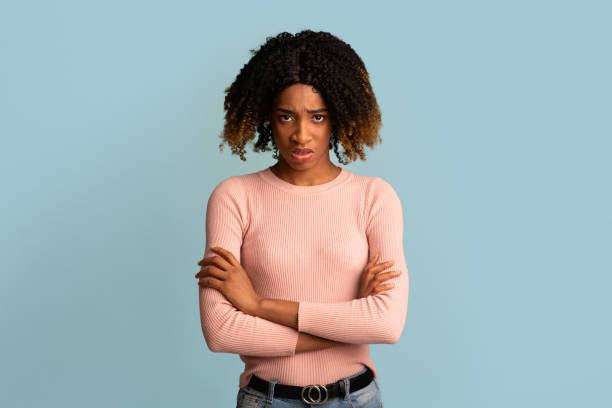 腕を組んで立っている若いアフリカ系アメリカ人女性の怒った肖像画 - disgust women african ethnicity human face ストックフォトと画像