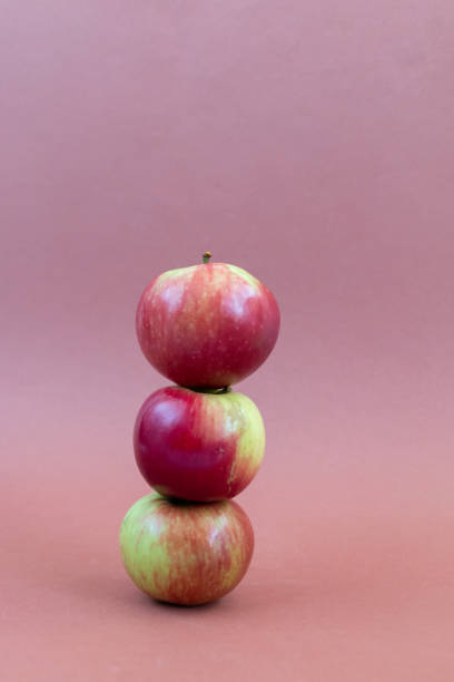 istock Stack of red fresh apples balancing against brown background 1342077064