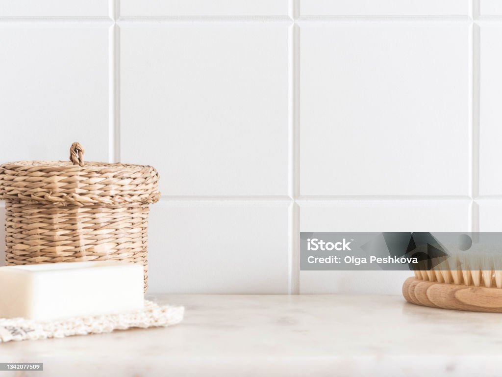 Bath background front view with straw box, wood brush for body and white soap on white marble shelf Bath background front view with straw box, wood brush for body and white soap on white marble shelf and wall tiles. Front view. Copy space Bathroom Stock Photo