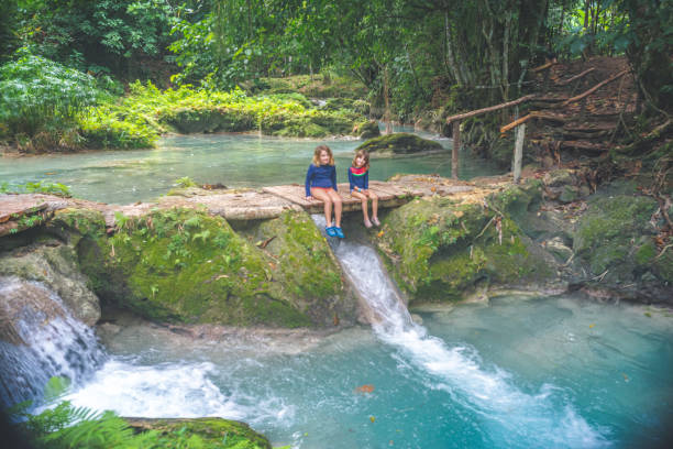 дети сидят у пышного водопада тропической лагуны на семейном отдыхе - waterfall tropical rainforest water jamaica стоковые фото и изображения