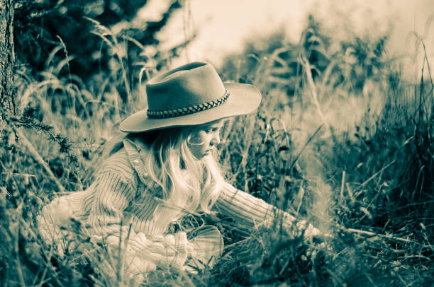 Straw Hat with a small bouquet of purple wildflowers on the green grass sunny day.Copy space