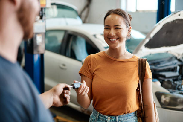 scatto di una donna che riceve le chiavi dell'auto - mechanic car auto mechanic auto repair shop foto e immagini stock
