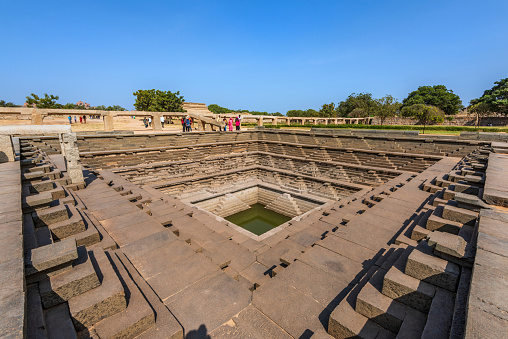 Hampi, Karnataka, India - January 14, 2020 : Symmetrical stepped square water tank (Stepwell) inside the Royal Enclosure at Hampi.