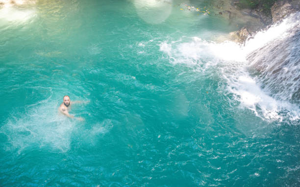istock Man swims alone in idyllic turquoise tropical lagoon with waterfall 1342086759