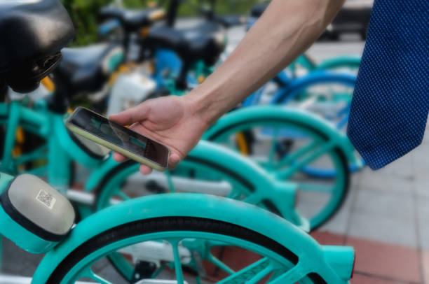 A man uses his smartphone to scan the QR code on the shared bicycle to open the lock, close-up of his hand