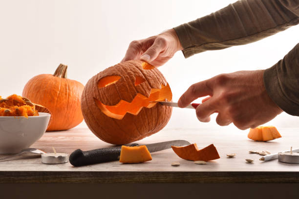 istock Man carving a pumpkin for the halloween party 1342088132