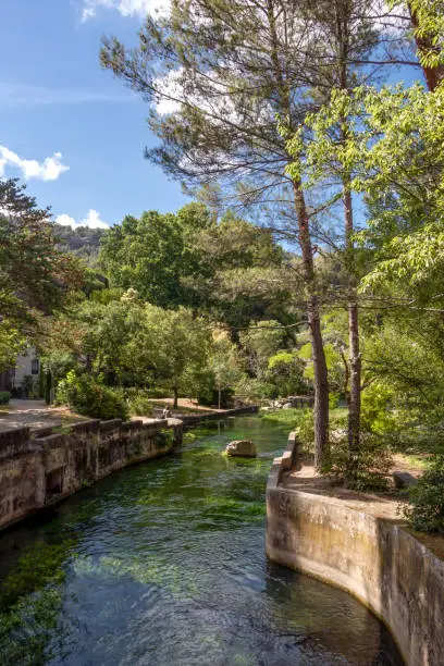 Fontaine-de-Vaucluse old town with river Sorgue in the foreground, charming medieval village in Vaucluse, Provence, southern France, Europe