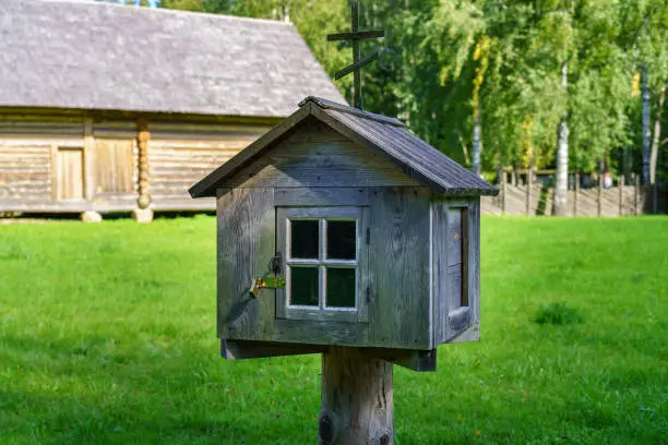 Photo of Old wooden mailbox on a post outside the house.