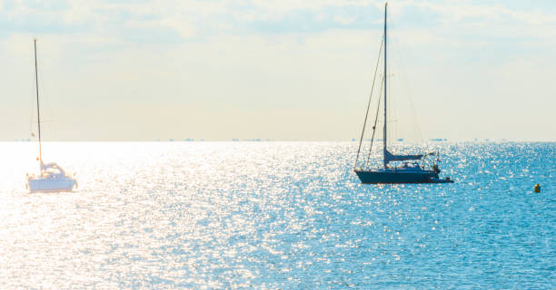 istock Sailboat sailing in bright silver colored sunlight reflected by the water surface of a lake under  a blue white sky in summer 1342088722