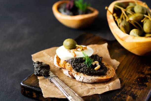istock Sandwich with slice of mozzarella cheese and tapenade, caper on dark rustic table background. Traditional Provence dish. Selective focus 1342090205