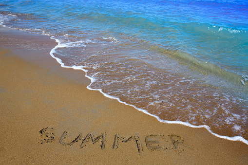 Summer spell written word in sand of a beach in vacation