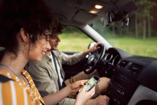 Beautiful young couple navigating with smart phone on a road trip stock photo
