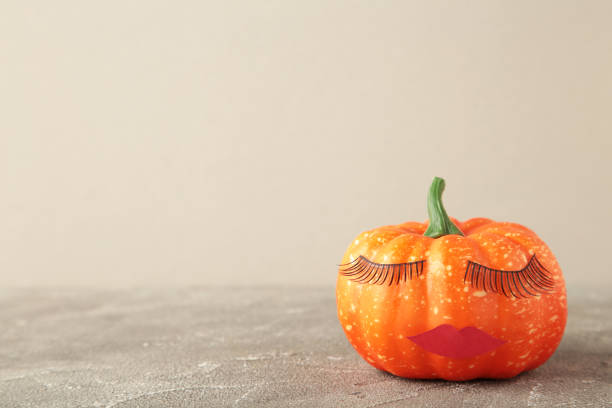 istock Halloween pumpkin with make up on grey. Minimal Holiday season concept background. 1342093813