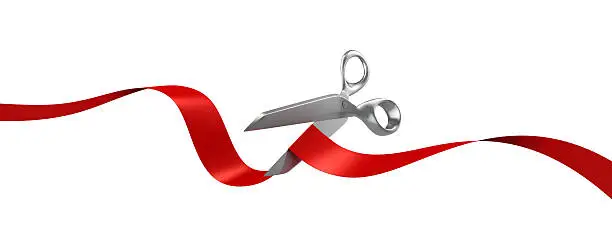 Photo of Silver scissors cutting red ribbon on white background