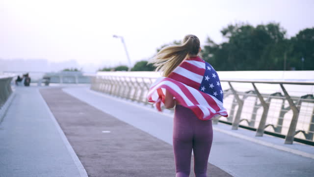 Athletic woman running with USA flag on her shoulders, representing her country