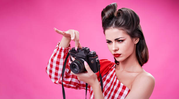 istock Beautiful brunette in retro style trying to set up an old camera 1342098207