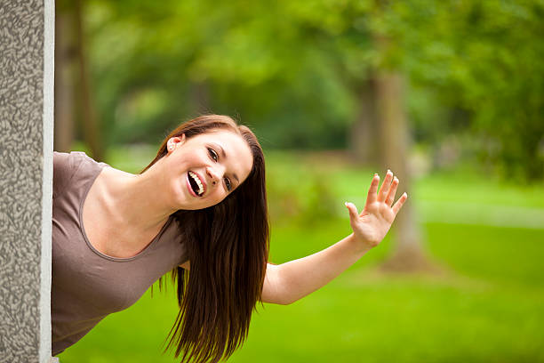 laughing young woman waving to something