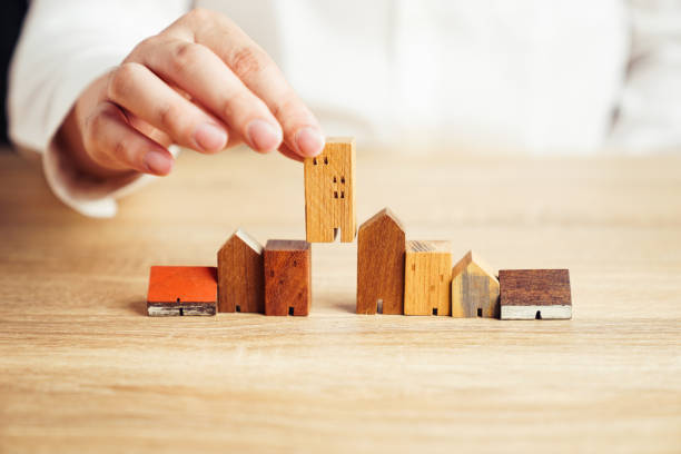Hand choosing house model from group of house on table, selective focus, Planning to buy property. Choose what's the best. A symbol for construction ,ecology, loan concepts stock photo