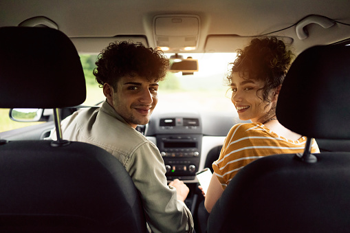 Cheerful young Caucasian couple traveling by car and having fun.