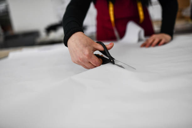 istock Female Designer Cutting Cloth With Scissors In Textile Factory 1342113300