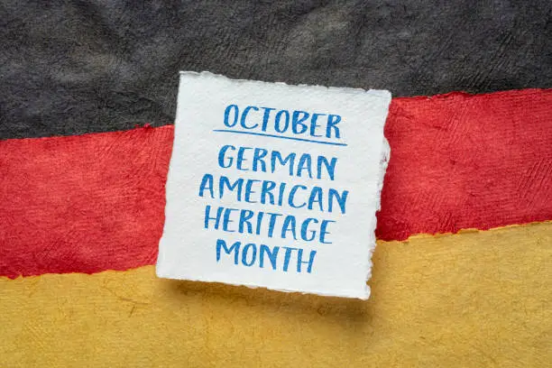 October - German American Heritage Month, square note against paper abstract in colors of Germany national flag, reminder of cultural event