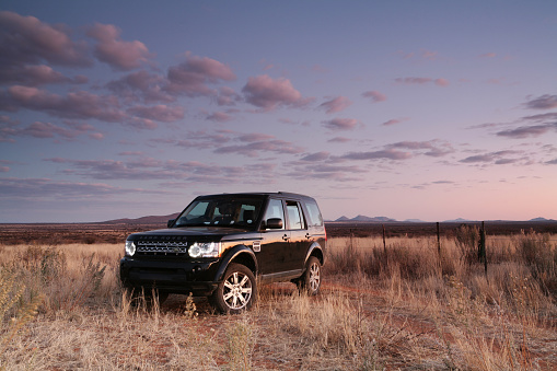 Windhoek, Namibia - July 2nd, 2010: A Black 2010 Land Rover Discovery 4 in a landscape, with sunset reflecting along the side of the vehicle.