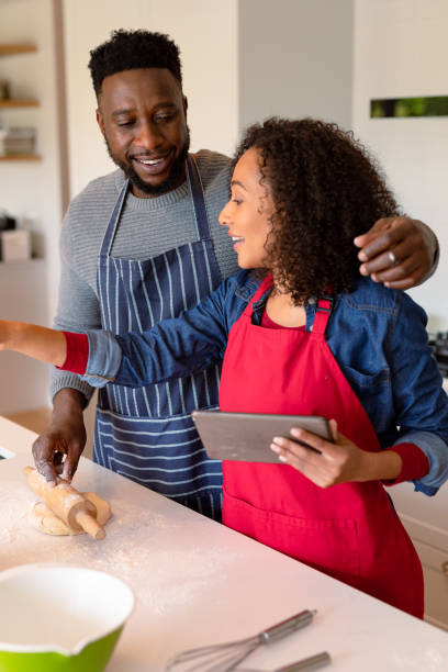 istock Happy african american couple wearing aprons, baking together and using tablet 1342115310