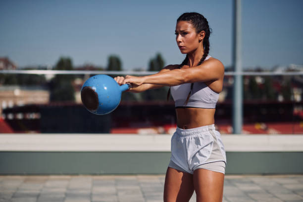 istock Young woman exercising outdoors with kettle bell weights 1342118007