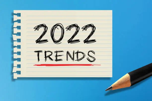Photo of 2022 Trends written on white paper with pencil on blue background. Communication business concept