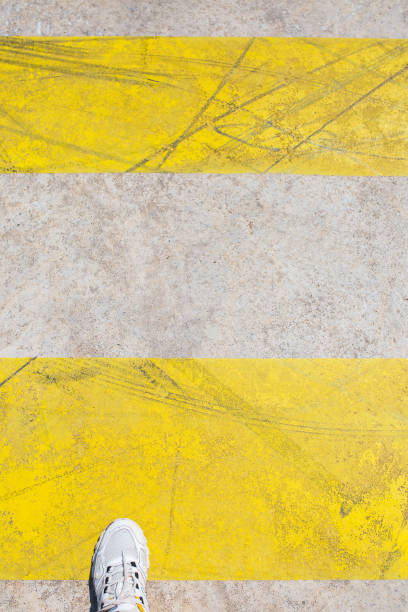 istock Foot steps on a pedestrian crossing with yellow marking lines 1342119024