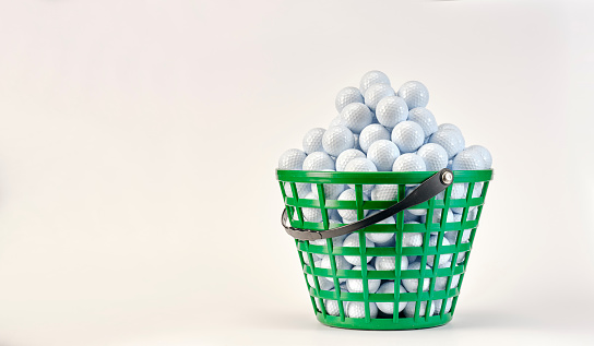 Basket full of golf balls ready to be used on the driving range. White background.